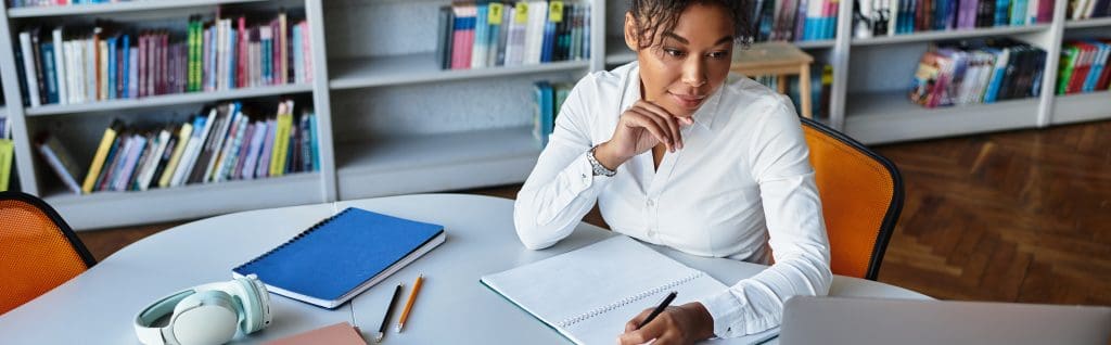 Educator focused on lesson planning, surrounded by books and resources.