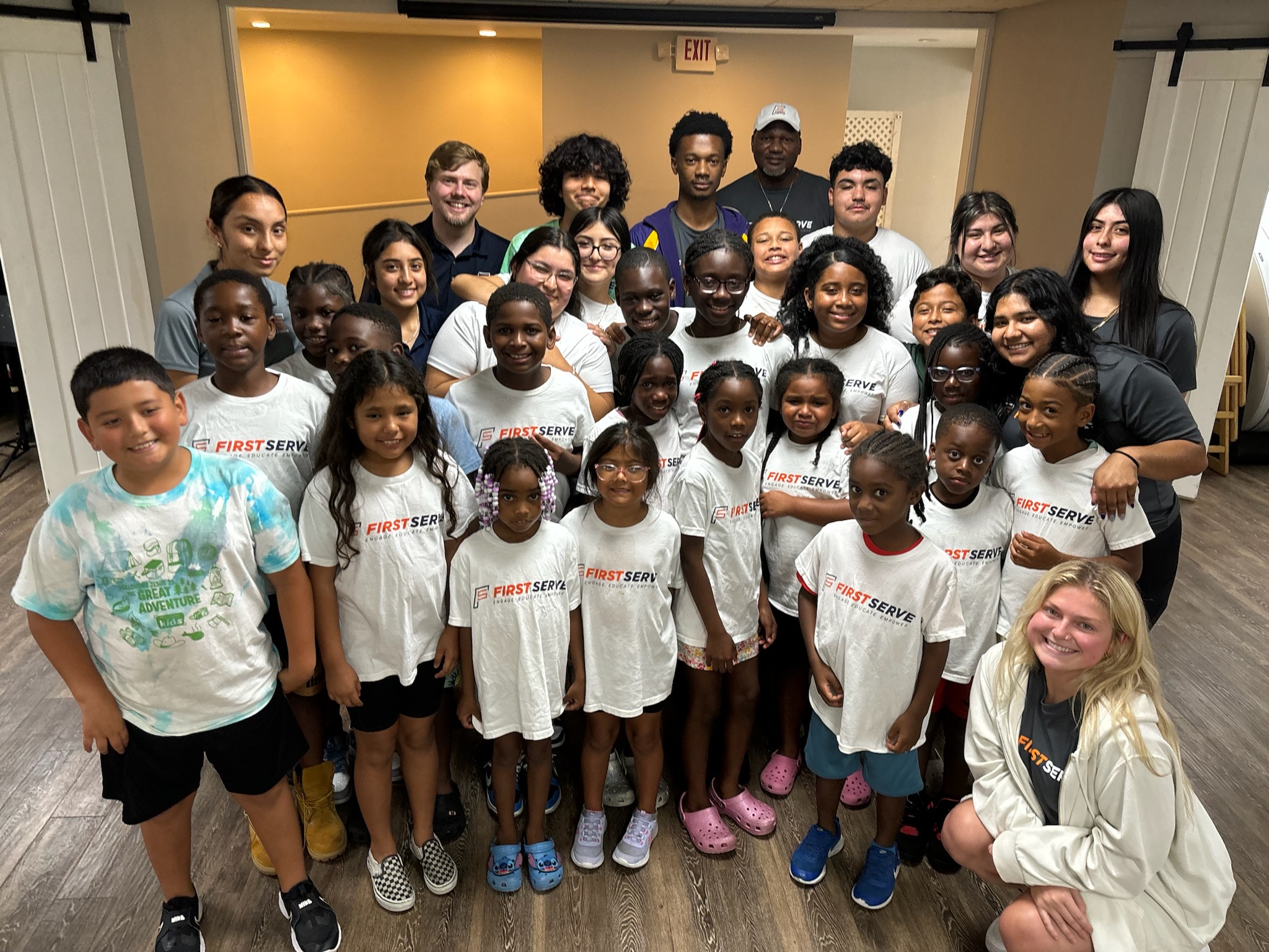 group of youth all wearing First Serve USA t-shirts.